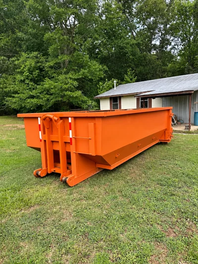 Orange roll-off dumpster on a grassy property beside a small home in the Medicine Park guide
