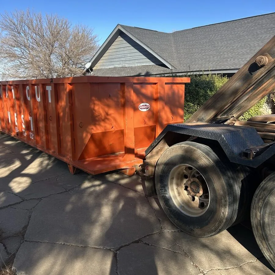 Truck delivering an orange roll-off dumpster beside a home in the Fort Sill area guide