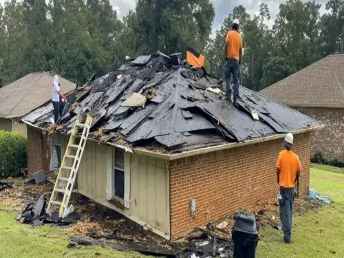 Roofing crew removing old shingles from a house during a roof tear-off