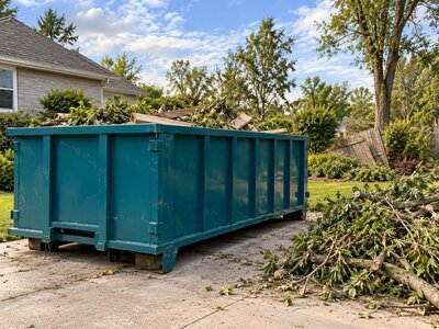 Roll-off dumpster and piles of branches during yard waste and storm debris cleanup